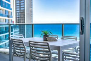 a white table with chairs and a plant on a balcony at H-Residences - GCLR in Gold Coast