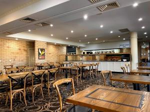 an empty restaurant with wooden tables and chairs at Western Heritage Motor Inn in Moranbah