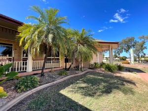 a house with palm trees in front of it at Western Heritage Motor Inn in Moranbah