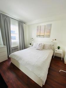 a white bedroom with a large white bed and wood floors at Ocean Walk by Miami Ambassadors in Miami Beach