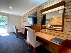 Zimmer mit einem Schreibtisch mit Stühlen und einem Spiegel in der Unterkunft Western Heritage Motor Inn in Moranbah