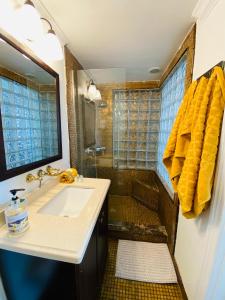 a bathroom with a sink and a shower with yellow towels at Ocean Walk by Miami Ambassadors in Miami Beach