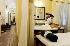 una mujer sentada en una cama en una habitación de hotel en Satri House Hotel en Luang Prabang