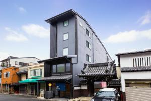 ein großes graues Gebäude mit einem Auto, das davor geparkt ist. in der Unterkunft Rinn Kitagomon in Kyoto