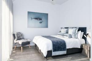 - une chambre avec un lit, une chaise et un tableau de baleine dans l'établissement Pacific Dawn on the Beach, à Wooli