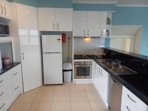 a kitchen with white cabinets and a white refrigerator at Heyfield Motel and Apartments in Lakes Entrance