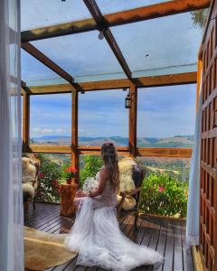 Una mujer con un vestido de novia sentada en un porche en Chalés da Serra Catarinense, en Bom Jardim da Serra