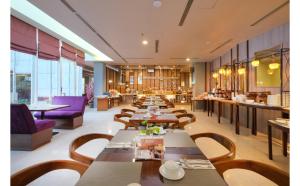 un restaurante con mesas largas y sillas moradas en Quest Hotel Simpang Lima - Semarang by ASTON en Semarang