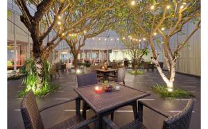 un restaurante con mesas, sillas, árboles y luces en Quest Hotel Simpang Lima - Semarang by ASTON, en Semarang