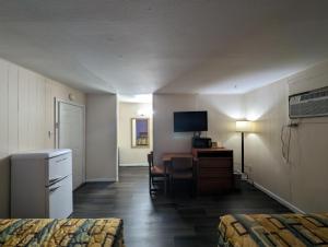 a hotel room with two beds and a desk and a television at Economy Inn Kingsville in Kingsville