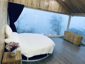 a bedroom with a white bed and a large window at Daisy SaPa - Venuestay in Sa Pa