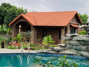 a brick house with a swimming pool in front of it at Đinh Gia Home Villa & Resort in Ninh Binh