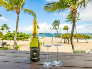 Una botella de champán y dos copas en una mesa cerca de la playa. en Studio CASA SUN, en Saint Martin