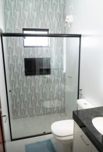 uma casa de banho com um WC e uma cabina de duche em vidro. em Capuzzo Flat 2 em Redenção