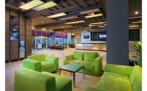a lobby with green chairs and a table at Quest Hotel Simpang Lima - Semarang by ASTON in Semarang