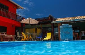 a pool with chairs and an umbrella next to a house at Pousada Bonito Cama e Café in Bonito