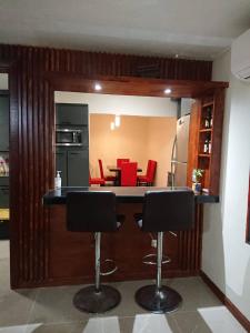 a kitchen with a bar with red chairs in it at Descanso y diversión 10 min de Puente Int Mission in Reynosa