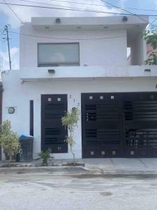 un edificio blanco con dos puertas negras de garaje en Descanso y diversión 10 min de Puente Int Mission en Reynosa