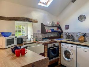 a kitchen with a sink and a washing machine at Birkerthwaire Stable-w41477 in Eskdale