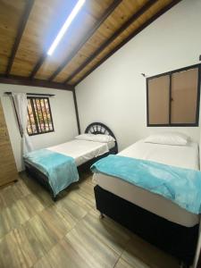 two beds in a room with a window at Eros Hostel & Brunch in Guatapé