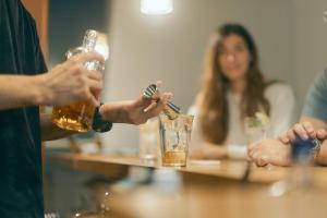 eine Gruppe von Menschen, die mit Getränken am Tisch sitzen in der Unterkunft Common de - Hostel & Bar in Fukuoka