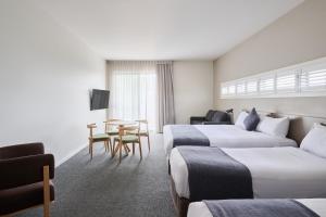 Habitación de hotel con 2 camas y mesa en Abode Gungahlin, en Canberra