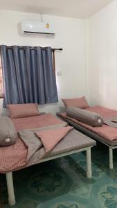 a room with three beds with pillows and a blue curtain at ศรีวดีโฮม(Sriwadee Home) in Ban Phai +6 photos