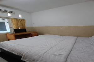 Schlafzimmer mit einem Bett, einem Schreibtisch und einem Fenster in der Unterkunft OYO 93207 Merah House in Pekanbaru