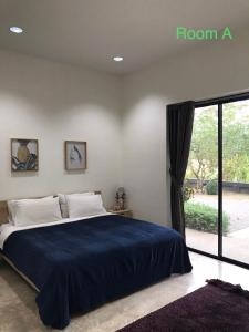 a bedroom with a bed with a blue blanket and a window at THE OAK’S in Chiang Rai