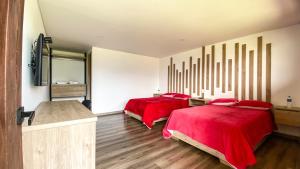 1 Schlafzimmer mit 2 Betten mit roter Bettwäsche und einem Spiegel in der Unterkunft Rio de piedras Hotel de alto rendimiento in Paipa