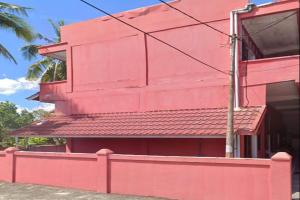 un edificio rosa con una recinzione rossa di fronte di OYO 93207 Merah House a Pekanbaru