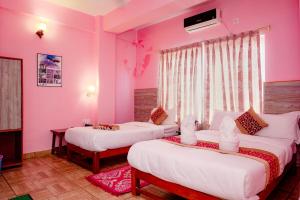 2 Betten in einem Zimmer mit rosa Wänden in der Unterkunft Hotel Peace Stupa in Pokhara