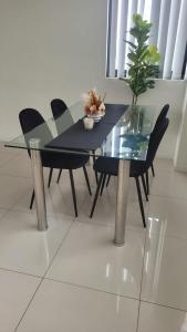 a glass dining table with black chairs and a plant at Modern 2 bedroom & 2 bathroom apartment with stunning Sydney CBD & Skyline Views! in Liverpool