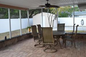 a patio with a table and chairs and a ceiling fan at Venice villa with heated pool, lanai, near beach in Venice