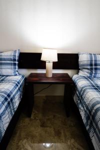 uma mesa com um candeeiro entre duas camas em HOTEL & RV PARK ROSA EVELYN em San Quintín
