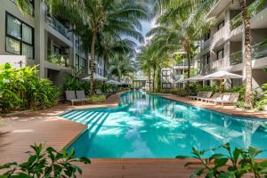 una piscina en medio de un edificio con palmeras en Diamond Resort Phuket Official Account en Bang Tao Beach