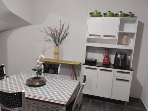 eine Küche mit einem Tisch und einem weißen Schrank in der Unterkunft Andres home casa J in Governador Valadares
