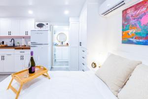 uma cozinha branca com um sofá e uma mesa com uma garrafa de vinho em Smart Tiny House Garden em Miami Gardens
