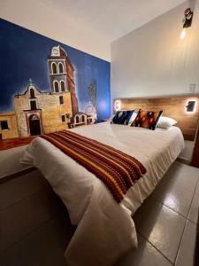 a bedroom with a large bed with a painting of a church at Baja Real Hotel Boutique in La Paz