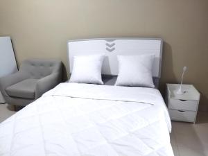 a bedroom with a white bed and a chair at Milestone City - Appartements à louer in Antananarivo