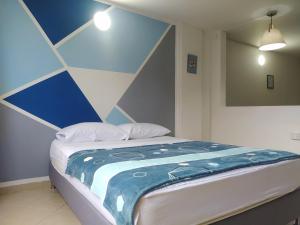 Cama en habitación con pared azul y blanca en Apartalofts Cali - Hermoso Loft Zona Oeste 25 m2, en Cali