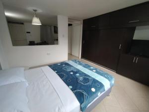 1 dormitorio con cama y espejo grande en Apartalofts Cali - Hermoso Loft Zona Oeste 25 m2, en Cali