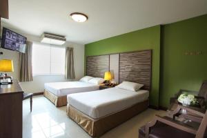 a hotel room with two beds and green walls at Rambuttri Village Plaza in Bangkok