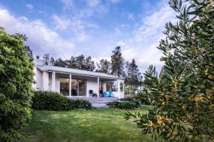 a white house with a porch and a yard at Driftwood in Coles Bay