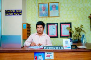 un homme assis à un bureau avec un ordinateur portable dans l'établissement Hotel Peace Stupa, à Pokhara