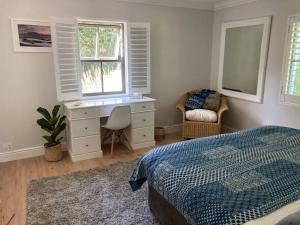 a bedroom with a bed and a desk and a window at Maroon Belles in Cape Town