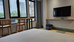 um quarto de hotel com uma cama e uma televisão de ecrã plano em 璿 旅 Syuan Hotel em Tainan