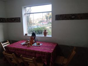 a table with a red table cloth and a window at Tukuypaj lodge in Amantani