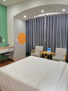 een ziekenhuiskamer met een bed en stoelen en een tafel bij POTA Hotel & Apartment in Da Nang