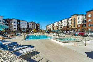 a swimming pool with lounge chairs and a building at Brand New Lux Apartment - Year Round Pool - HAFB in Clearfield